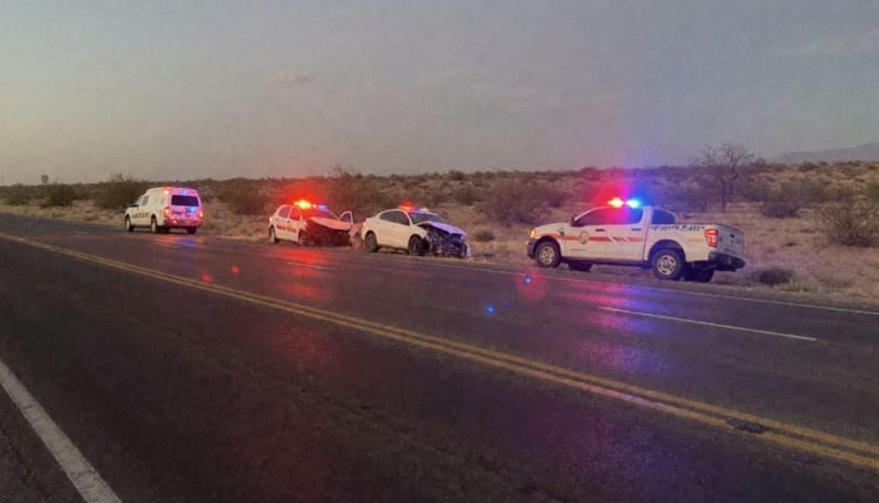 Dos automóviles dañados en la carretera después del impacto, con luces de emergencia iluminando la escena al amanecer