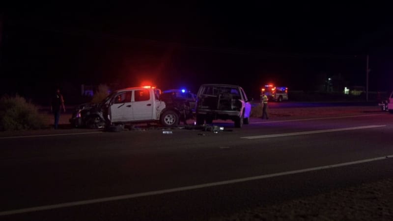 Vehículos dañados sobre la carretera con luces de emergencia iluminando la escena nocturna