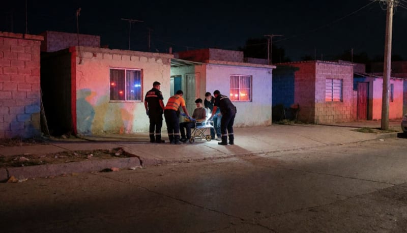 Paramédicos atendiendo a una persona herida en una calle residencial de Chihuahua durante la noche