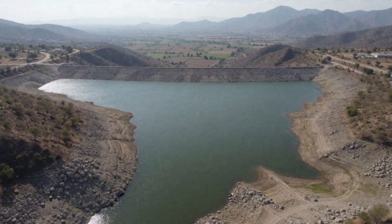 Presa con nivel de agua bajo rodeada de tierra seca y bancos rocosos en el árido paisaje del norte de México