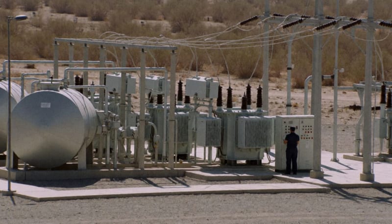 Estación de bombeo de agua con infraestructura eléctrica en el desierto, tanques metálicos y transformadores bajo el sol