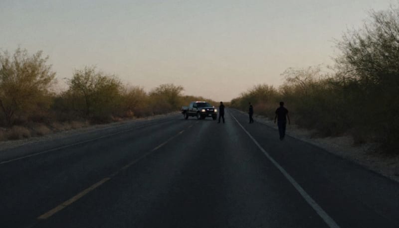 Carretera rural en la noche con luces de emergencia reflejadas en el asfalto desértico