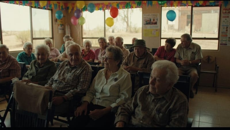 Adultos mayores reunidos en un salón comunitario, conversando y sonriendo durante una celebración