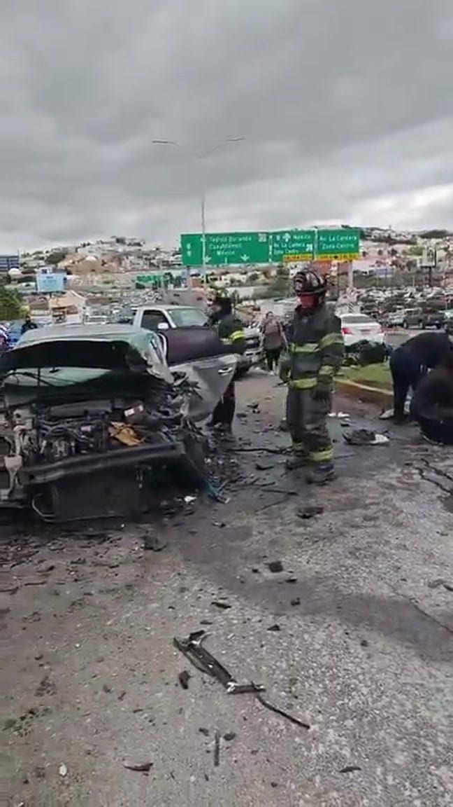 Bomberos junto al Volkswagen Passat destrozado en el Periférico de la Juventud