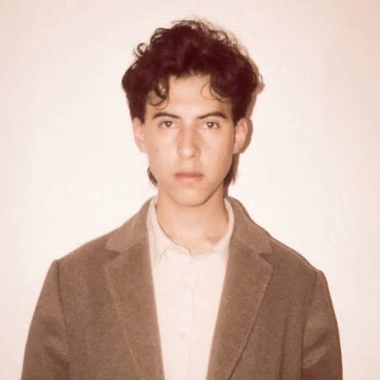 Retrato del poeta Sergio F. 'Checo' Mendoza, de saco claro, mirando a la cámara.