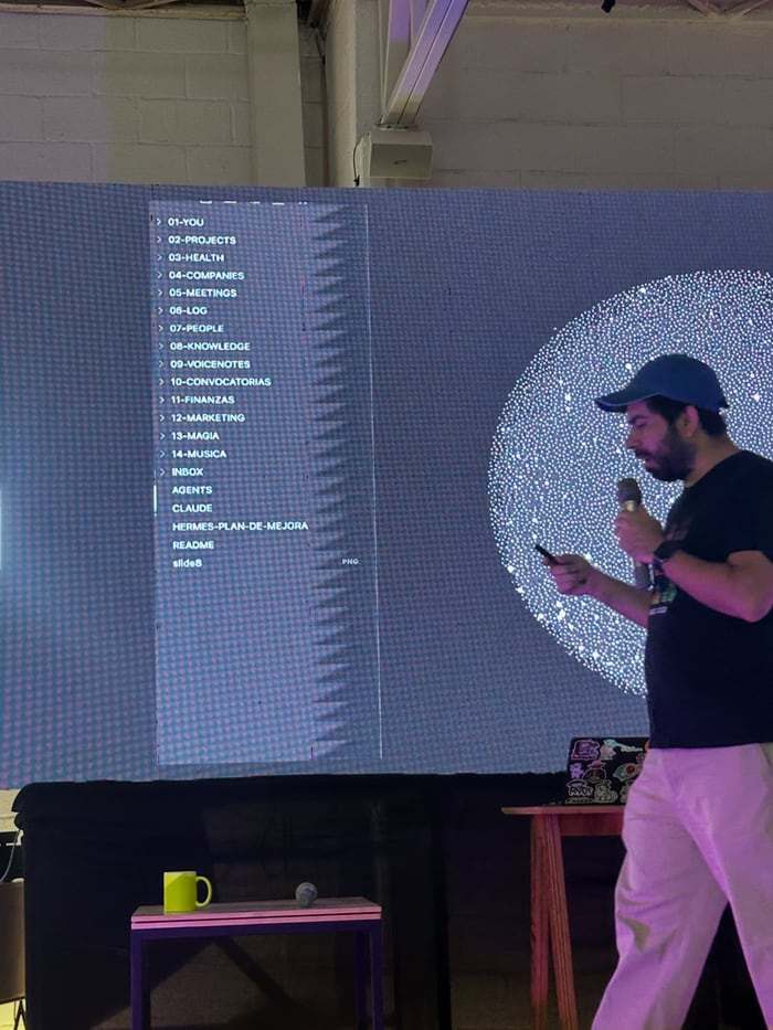 Magio Bustillos habla con un micrófono frente a una pantalla que muestra las carpetas de su sistema de notas