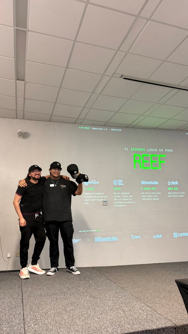 El equipo de REEF en el escenario frente a la pantalla que lo anuncia como segundo lugar