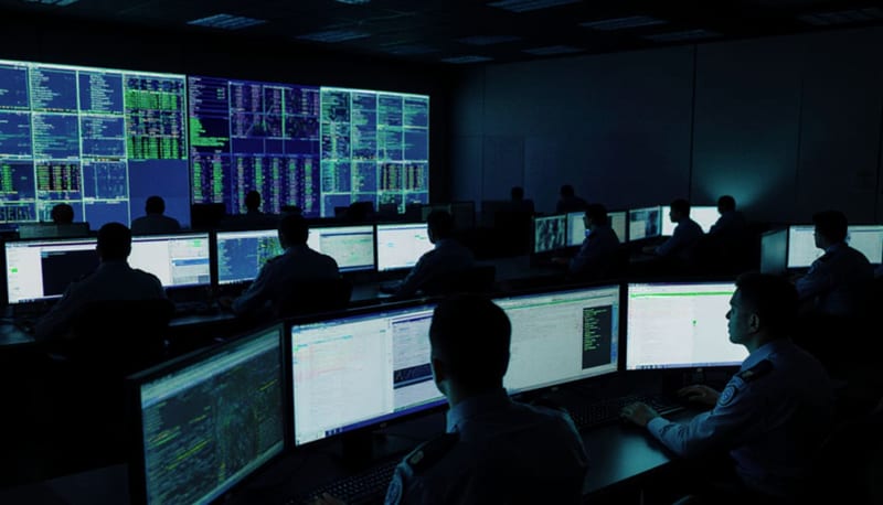Oficiales monitoreando pantallas en una sala de operaciones cibernéticas durante labores de vigilancia digital