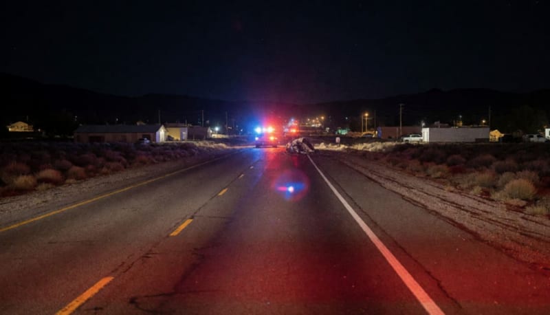 Carretera nocturna del desierto con luces de emergencia iluminando la escena de un accidente