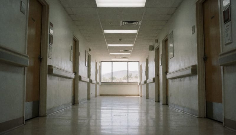 Pasillo vacío de un edificio de salud con puertas selladas y iluminación institucional