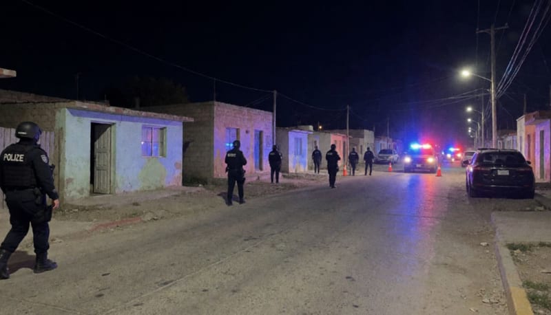Patrullas de la policía con luces activadas frente a viviendas en una calle residencial por la noche