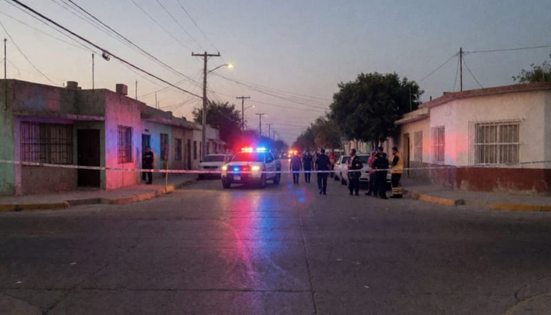 Escena de un enfrentamiento armado con perimetral policial acordonado y luces de emergencia en una calle de Chihuahua