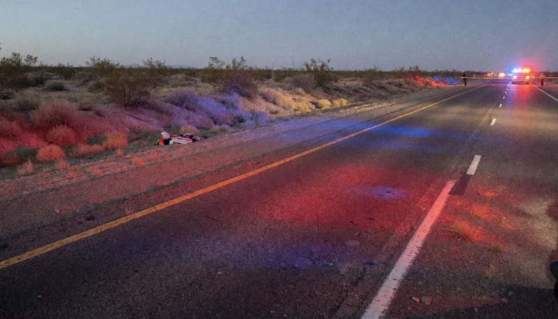 Carretera federal del desierto chihuahuense con luces de emergencia y zona acordonada al atardecer