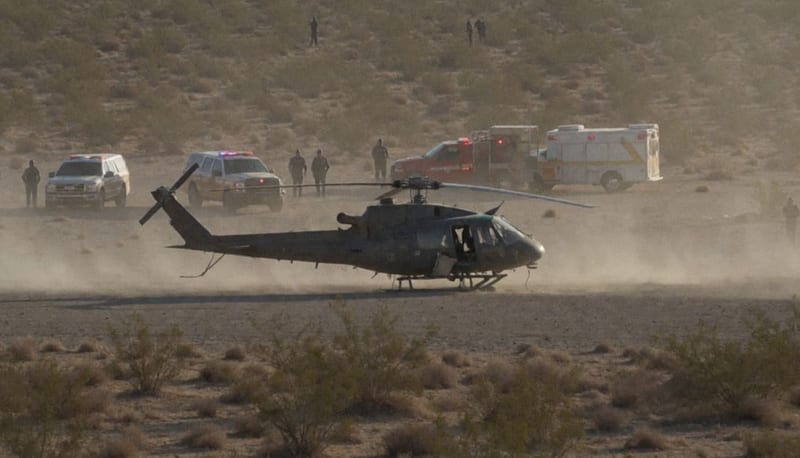 Helicóptero dañado en una zona de aterrizaje desértica con vehículos de emergencia en la región fronteriza