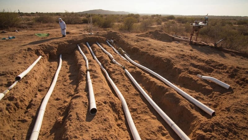 Sitio de excavación en terreno desértico con personal forense trabajando en zanjas marcadas en el suelo árido