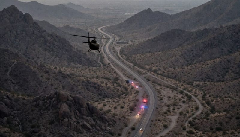 Terreno desértico montañoso de la región fronteriza con vehículos de emergencia en la distancia al atardecer