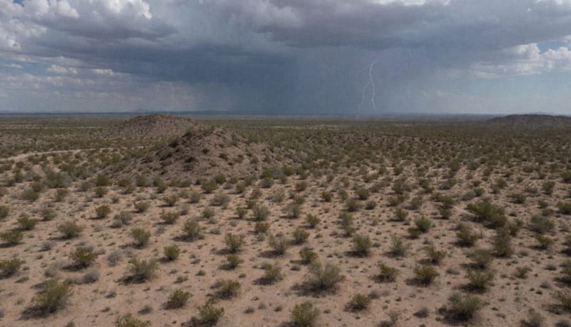 Nublazón sobre el desierto de Chihuahua con cortinas de lluvia visible en el horizonte y relámpagos iluminando las nubes oscuras