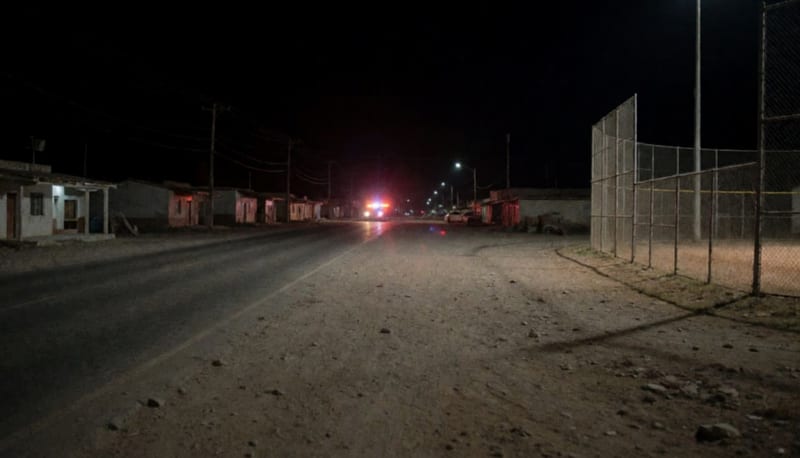Orilla de una carretera de noche con luces de emergencia a lo lejos
