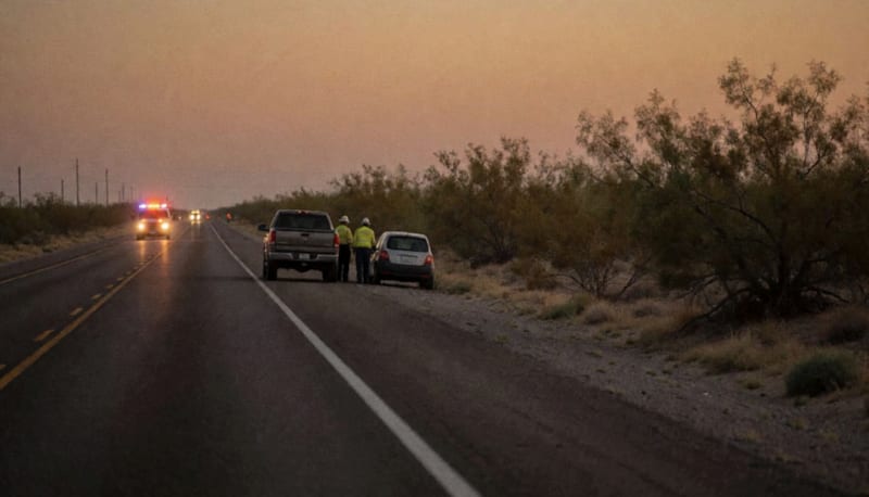 Carretera en el desierto de Chihuahua al anochecer con luces de emergencia a lo lejos junto a dos vehículos accidentados