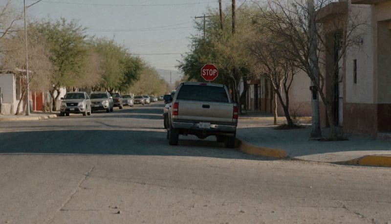 Camión estacionado sobre una calle residencial con señal de alto parcialmente oculta de fondo