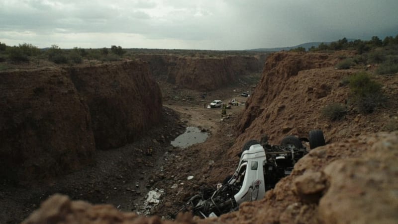 Automóvil volcado en el fondo de un barranco con escombros alrededor y terreno rocoso irregular