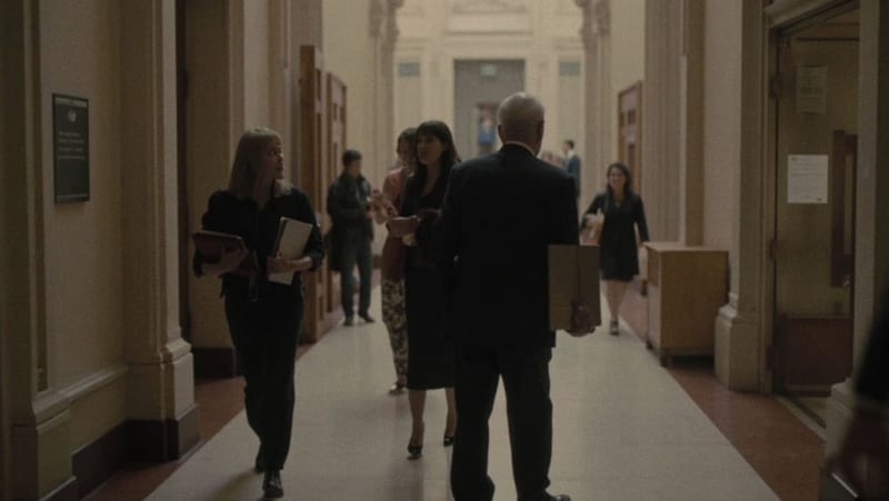Personas en los pasillos de un edificio legislativo acercándose a una oficina de trámites
