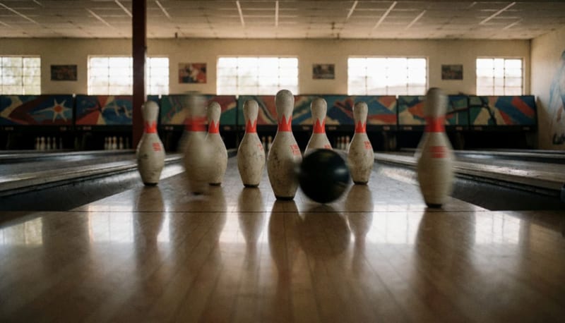 Pinos de boliche dispersados tras el impacto en la pista de un salón de boliche local