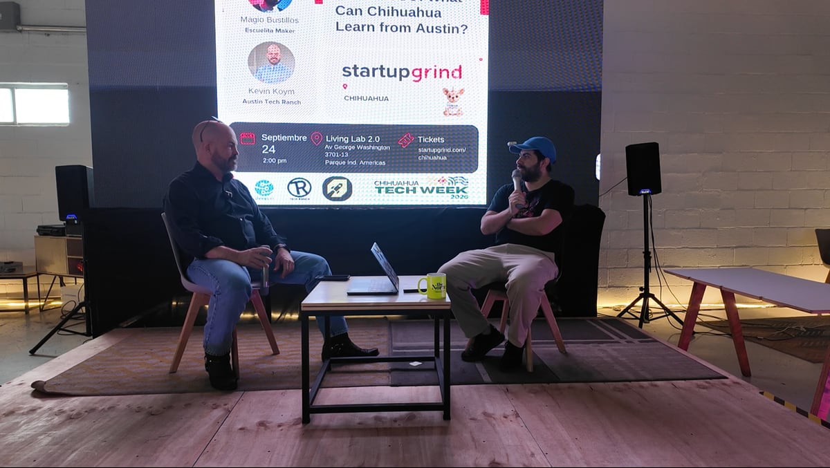 Kevin Koym y Magio Bustillos conversan sentados en el escenario del Living Lab, frente a la pantalla del evento de Startup Grind Chihuahua