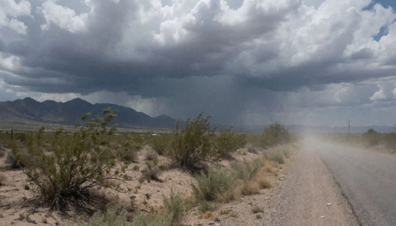 Nubes oscuras reuniéndose sobre el paisaje árido de Chihuahua con lluvia comenzando a caer