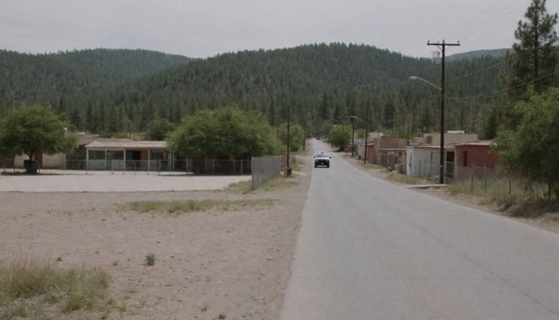 Camino rural hacia un pueblo de la sierra de Chihuahua, con una escuela vacía al fondo