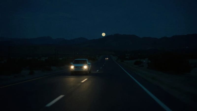 Camioneta circulando por una carretera desértica oscura bajo el cielo nocturno de Chihuahua