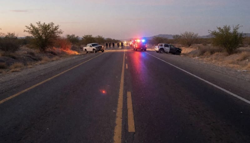 Carretera del norte de México con vehículos dañados y luces de emergencia activadas al atardecer