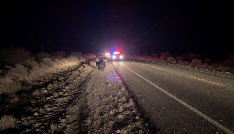 Carretera desierta de noche con luces de patrullas iluminando la escena de un robo de motocicleta