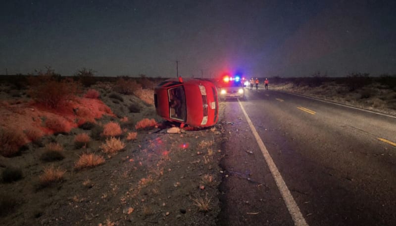 Vehículo volcado iluminado por luces de emergencia en carretera del desierto chihuahuense durante la noche